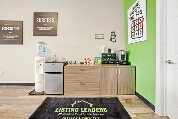 Student lounge at Listing Leaders Northwest School of Real Estate with coffee bar, fridge, and branded rug.