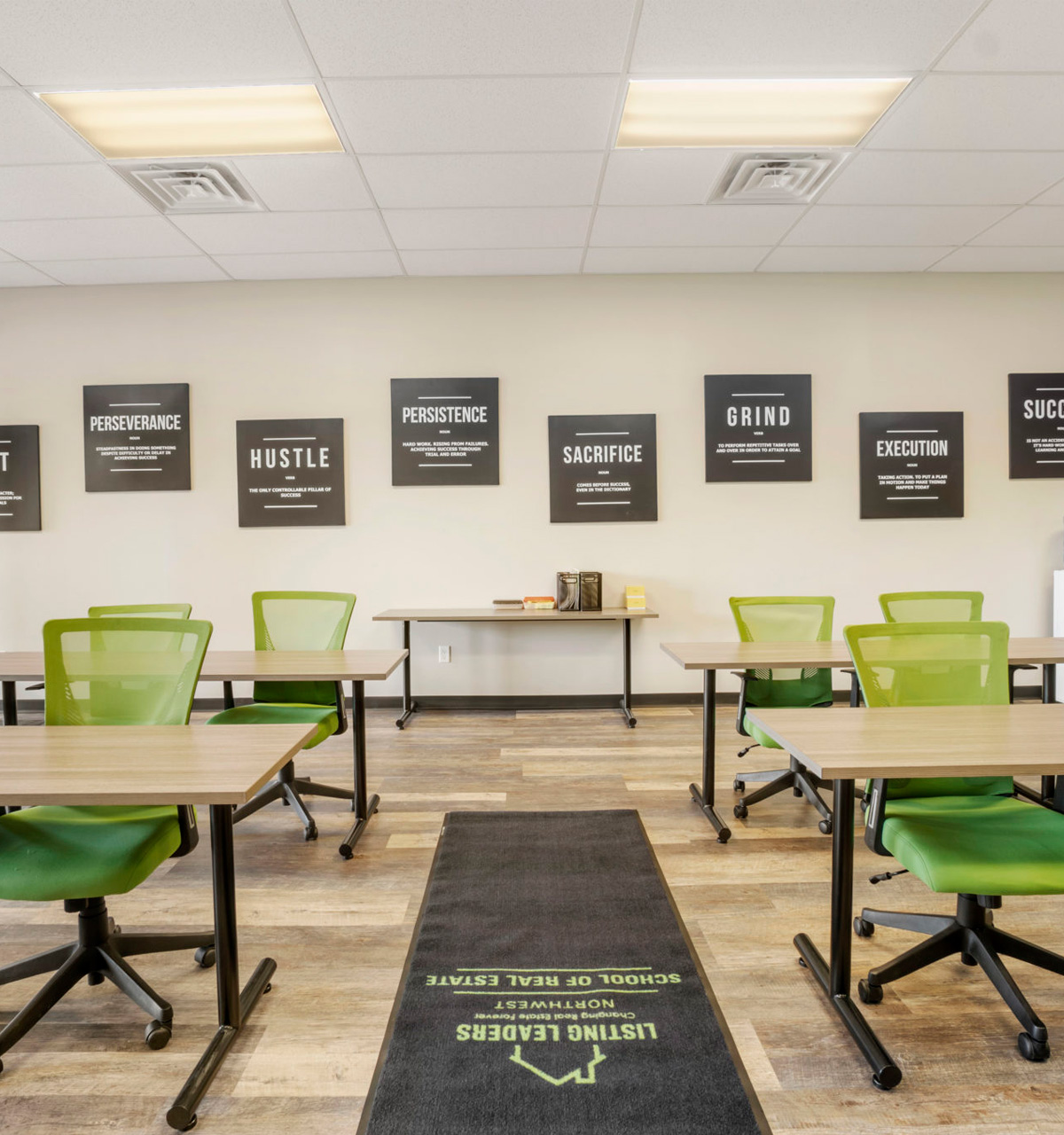 Classroom interior at Listing Leaders School of Real Estate with green seating and branded school entrance rug.